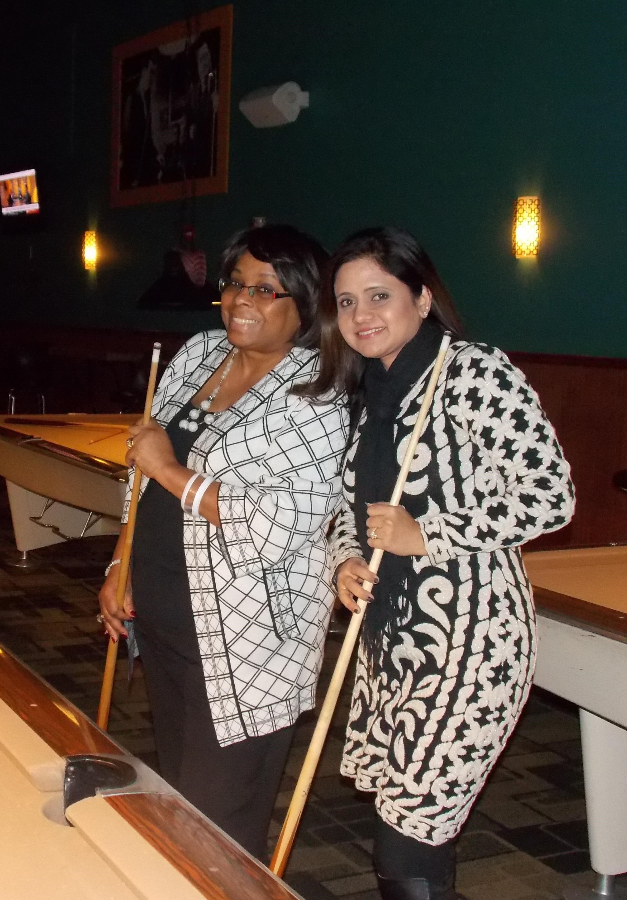 Seniorlink employees smiling while playing a game of pool